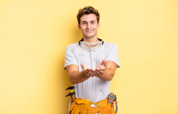 smiling happily with friendly, confident, positive look, offering and showing an object or concept. handyman concept - Photo, image