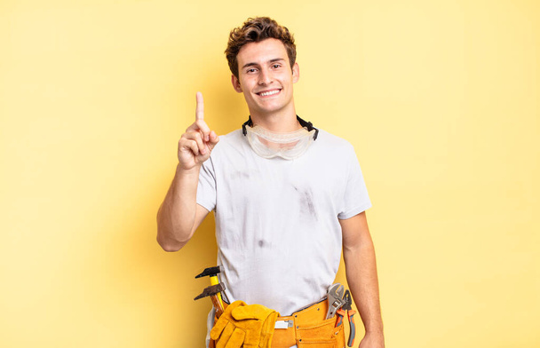 smiling and looking friendly, showing number one or first with hand forward, counting down. handyman concept - Photo, image