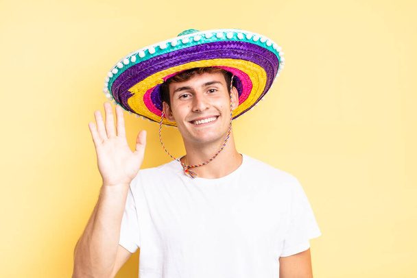 smiling happily and cheerfully, waving hand, welcoming and greeting you, or saying goodbye. mexican hat concept - Photo, Image