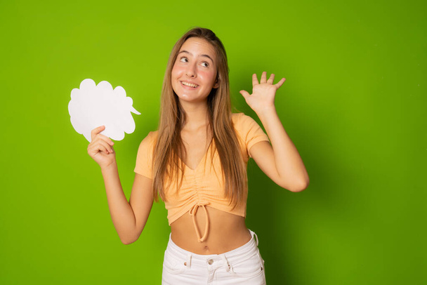 Portrét atraktivní veselá dívka držící papírové mraky kopírovat prostor izolovaný přes zelené pozadí - Fotografie, Obrázek