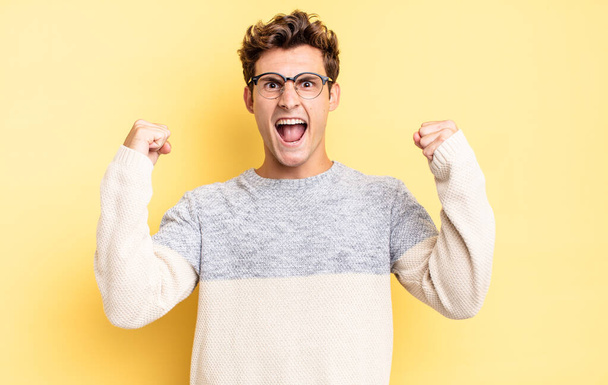 young teenager boy shouting aggressively with an angry expression or with fists clenched celebrating success - Photo, Image