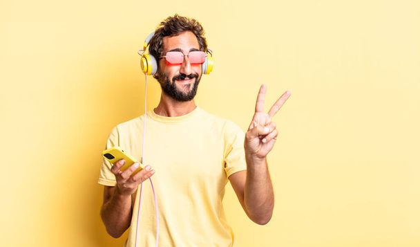 expressive crazy man smiling and looking friendly, showing number two with headphones - Foto, Bild