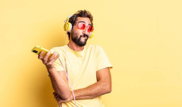 expressive crazy man shrugging, feeling confused and uncertain with headphones - Foto, Bild