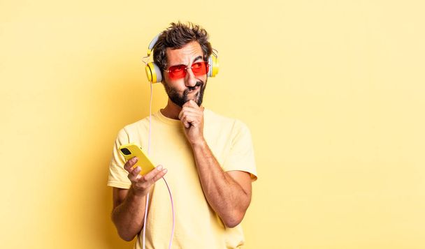 expressive crazy man thinking, feeling doubtful and confused with headphones - Photo, image