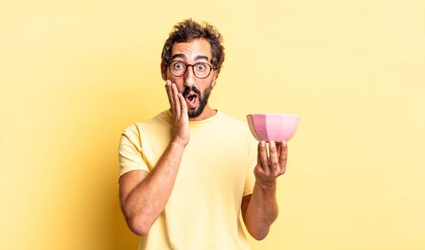 expressive crazy man feeling shocked and scared and holding a pot - Photo, Image