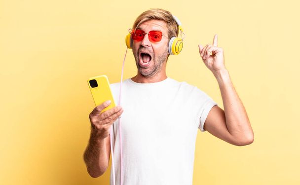 blond adult man feeling like a happy and excited genius after realizing an idea with headphones - Photo, image