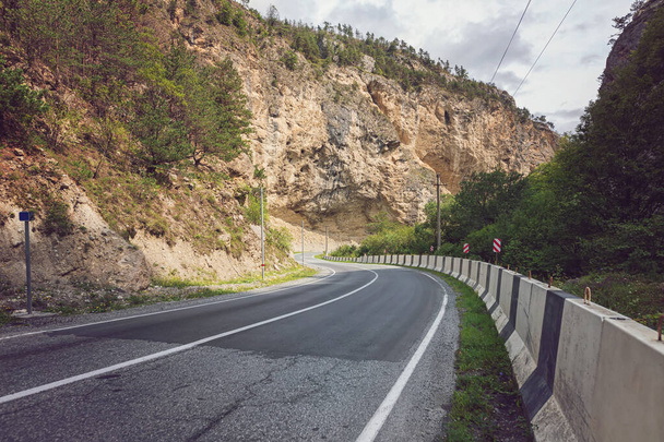Une route asphaltée avec une barrière de protection en béton dans une zone montagneuse - Photo, image