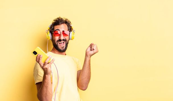 expressive crazy bearded man listening music with headphones and sartphone - Φωτογραφία, εικόνα