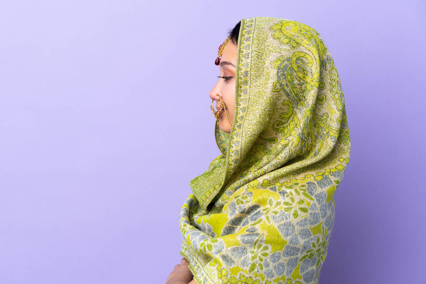 Indian woman isolated on purple background in lateral position - Photo, Image