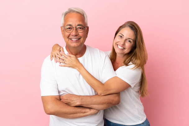 Ζευγάρι μέσης ηλικίας απομονωμένο σε ροζ φόντο αγκαλιάζει - Φωτογραφία, εικόνα