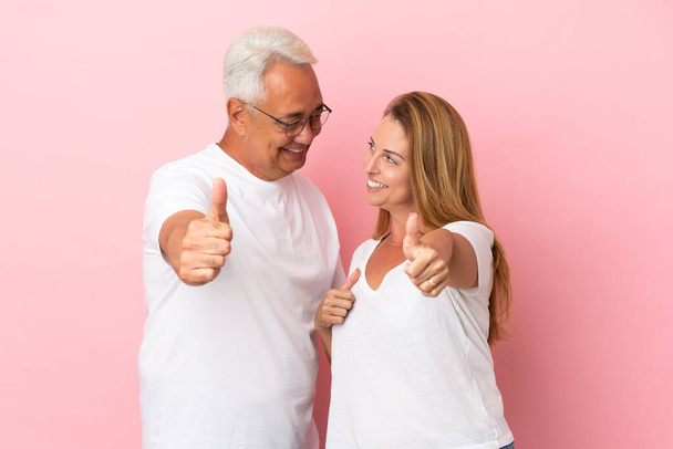 Пара средних лет изолированы на розовом фоне давая большой палец вверх жест - Фото, изображение
