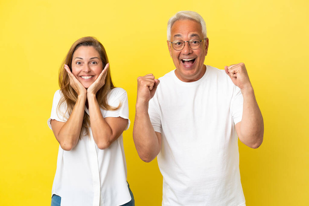 Ζευγάρι μέσης ηλικίας απομονωμένο σε κίτρινο φόντο γιορτάζει μια νίκη - Φωτογραφία, εικόνα