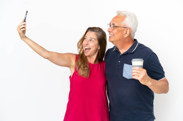 Coppia di mezza età isolata su sfondo bianco facendo un selfie con il cellulare - Foto, immagini