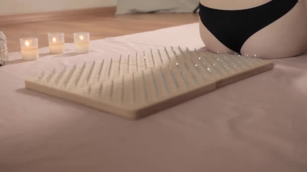 A beautiful woman lying on her back on a board with nails. Therapy through pain is its acceptance. Extreme yoga of relaxation and self-development  - Footage, Video