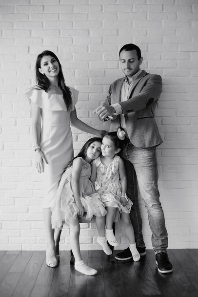 Красивая молодая семья с дочерьми на фотосессии в белой студии - Фото, изображение