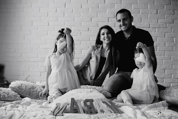 Mooie jonge familie met dochters bij een fotoshoot in een witte studio - Foto, afbeelding