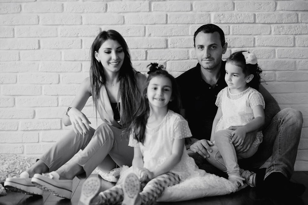 Красивая молодая семья с дочерьми на фотосессии в белой студии - Фото, изображение