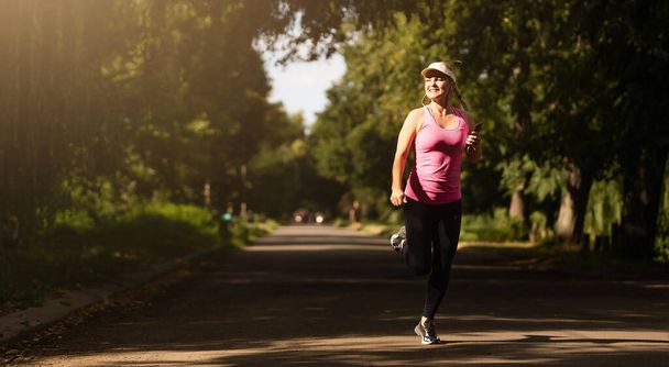Uma mulher em fuga. Feminino corredor Jogging durante o treino ao ar livre em um parque. Menina bonita ajuste. Ao ar livre. Perda de peso - Foto, Imagem