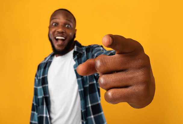 Emocionado hombre africano señalando a la cámara, fondo amarillo - Foto, imagen