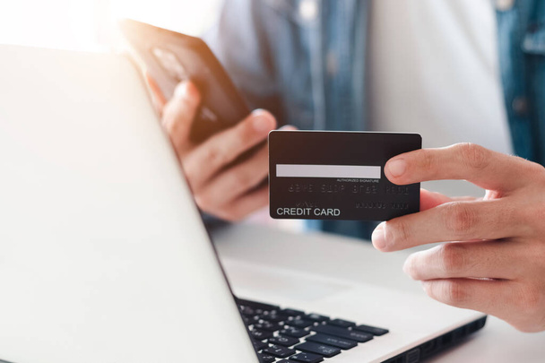 Üzletember kézben tartja hitelkártya segítségével laptop az online vásárlás, miközben a megrendelések otthon. üzleti, életmód, technológia, e-kereskedelem, digitális banki és online fizetési koncepció. - Fotó, kép