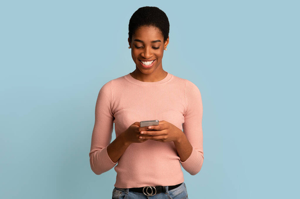 Komunikacja mobilna. Happy Black Kobieta za pomocą nowoczesnego smartfona do wiadomości z przyjaciółmi - Zdjęcie, obraz