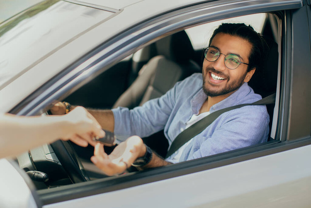 Χαρούμενος Άραβας άνθρωπος που παίρνει το κλειδί του αυτοκινήτου από μισθώνοντας υπάλληλος υπηρεσιών - Φωτογραφία, εικόνα