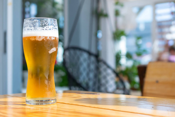 пиво в стакане на коричневом столе с размытым фоном - Фото, изображение