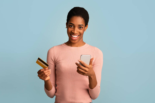 モバイル決済。スマートフォンやクレジットカードで幸せなアフリカ系アメリカ人女性の肖像 - 写真・画像