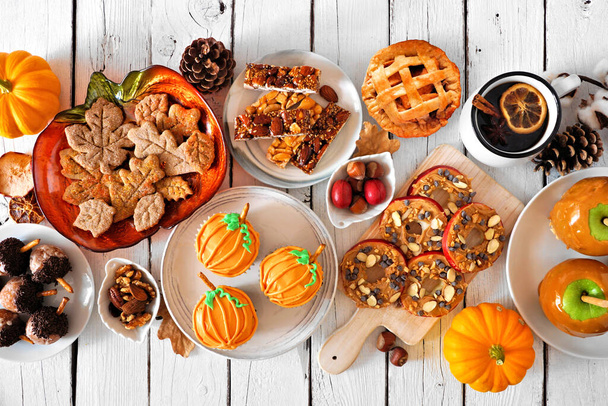 Herbstliche Desserts Tisch Szene mit einer Vielzahl von süßen herbstlichen Leckereien. Blick über einen weißen Holzhintergrund. - Foto, Bild