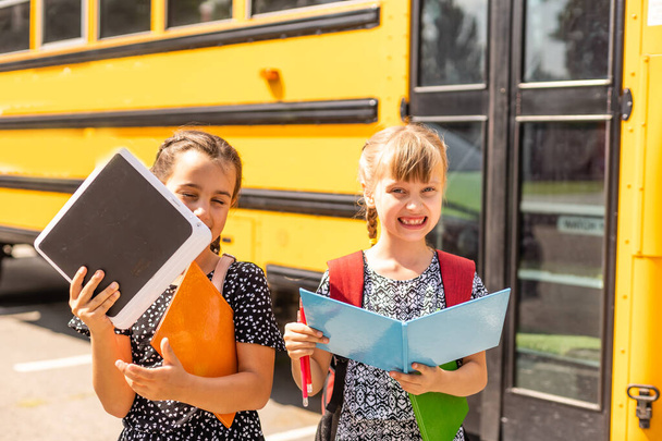 Веселі дівчата поруч зі шкільним автобусом. Зворотній бік. Повернутися до концепції школи
. - Фото, зображення
