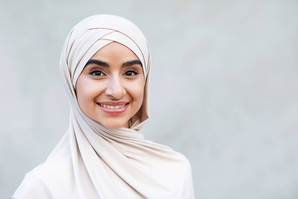 Cabeza de alegre linda milenaria mujer de Oriente Medio en hijab mira a la cámara - Foto, Imagen