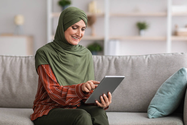 Muslim Lady Using Digital Tablet Browsing Internet Sitting At Home - Fotografie, Obrázek