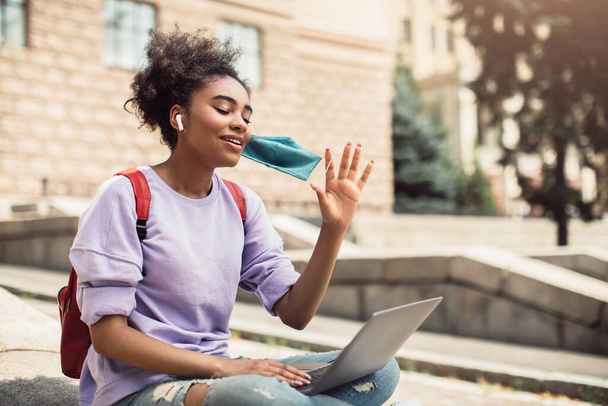 Musta tyttö tekee videopuhelun kannettavan tietokoneen heiluttaen kättä ulkona - Valokuva, kuva
