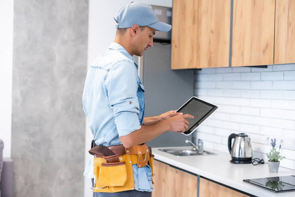 Male worker types on a tablet, kitchen renovation - 写真・画像