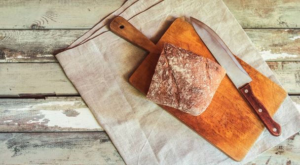 Rye bread and kitchen knife on aged wooden table. Top view, copy space. - Zdjęcie, obraz