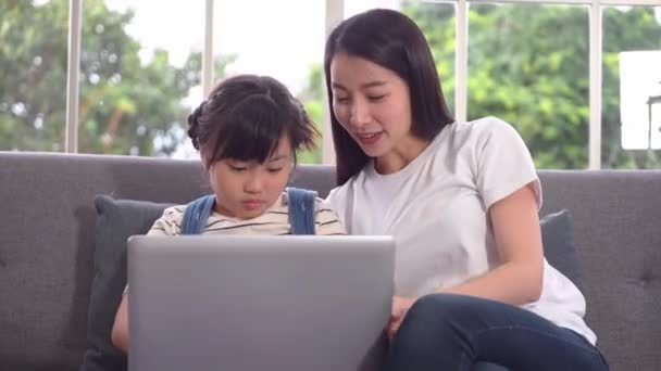 Mère apprend à sa fille à utiliser l'ordinateur portable pour surfer sur Internet et faire de la communication en ligne à la maison. - Séquence, vidéo