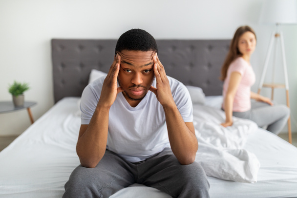 性的問題、関係危機。ストレスを受けた黒人男性がベッドに座って寺院をマッサージ家族の困難の疲れ - 写真・画像