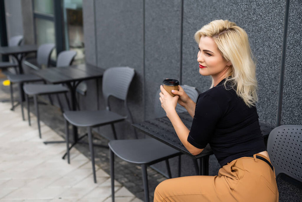 Young woman having a breakfast with coffee at the cafe terrace - Photo, Image