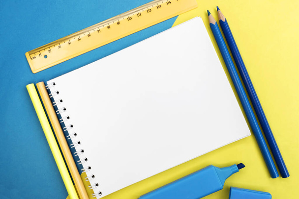 On a colored background among pencils with a ruler there is a notebook with a place for text. Educational concept - Foto, Imagen