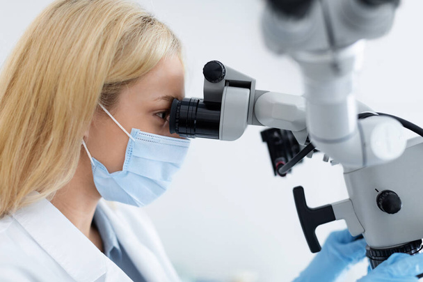 Dentystka patrząca na mikroskop dentystyczny, innowacyjny sprzęt stomatologiczny - Zdjęcie, obraz