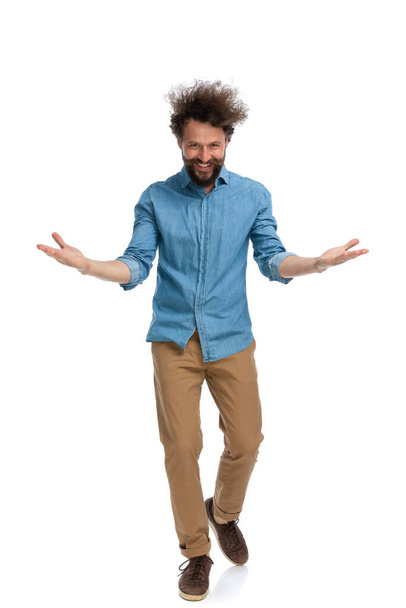 excited casual man greeting someone with open arms and a smile on his face on white background - Foto, imagen