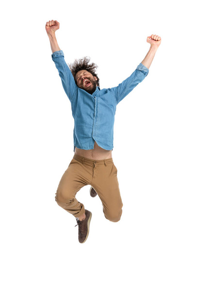 casual man full of excitement is jumping in the air and celebrating the victory on white background - Foto, afbeelding