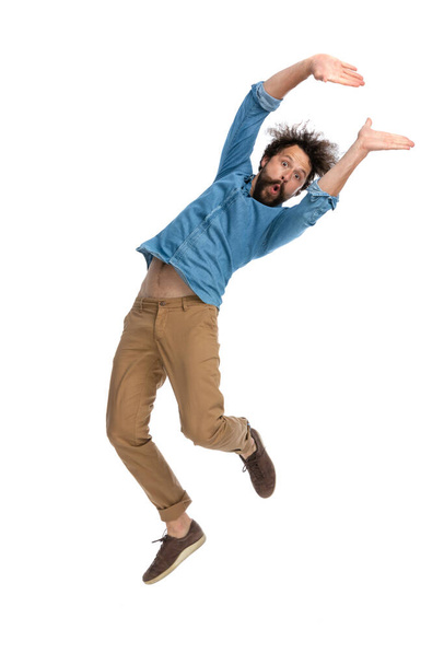 guapo hombre casual agitando su cuerpo mientras salta sobre fondo blanco estudio - Foto, imagen