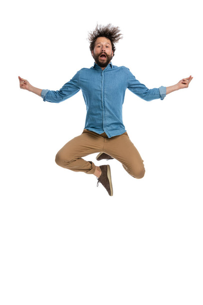 atractivo hombre casual saltando en una posición de yoga sobre fondo blanco - Foto, imagen