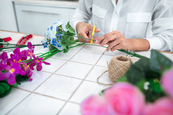 Evde suni çiçek dekorasyonu düzenleyen genç kadın çiçekçi, yapay çiçek, el işi ve el yapımı konsept düzenliyor.. - Fotoğraf, Görsel