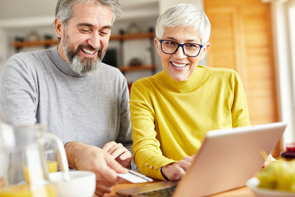 ηλικιωμένο ζευγάρι ευτυχής φορητό υπολογιστή online αγορές χρεωστική πιστωτική κάρτα παραγγελία ηλεκτρονικού εμπορίου - Φωτογραφία, εικόνα