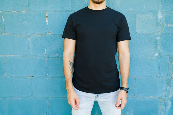 Crop näkymä latino nuori mies osoittaa hänen tyylikäs musta t-paita trendikäs custom print - Valokuva, kuva