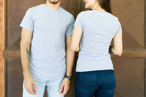 Widok na zboże atrakcyjnej pary w szarych t-shirtach, pokazując projekt nadruku z przodu i z tyłu - Zdjęcie, obraz