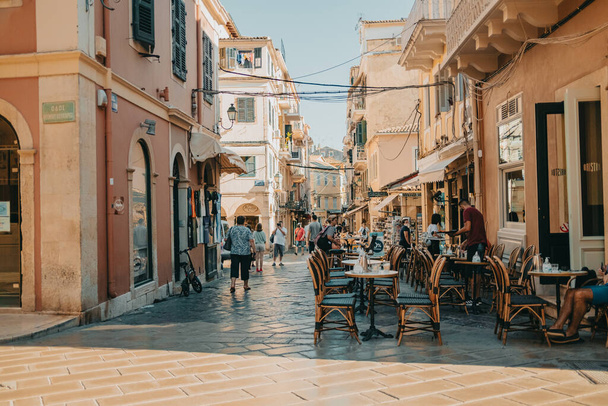 Corfu, Greece - September 2021. Beautiful cozy narrow street in old greek town. Historic european centre with cafe and people, tourists. Cityscape concept. - Foto, Imagem