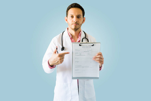 Worried doctor with a serious and somber expression pointing to a medical chart or prescription  - Фото, изображение